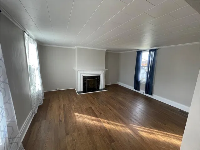 an empty room with wooden floor and fireplace