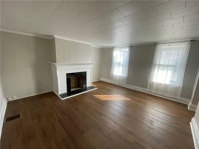 an empty room with wooden floor and fireplace