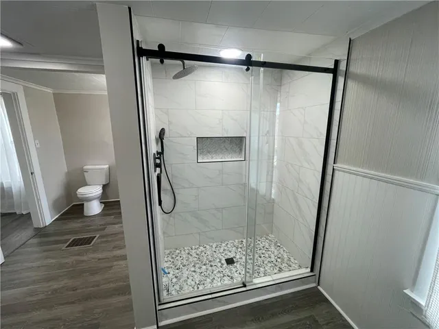 a bathroom with a glass door shower and toilet