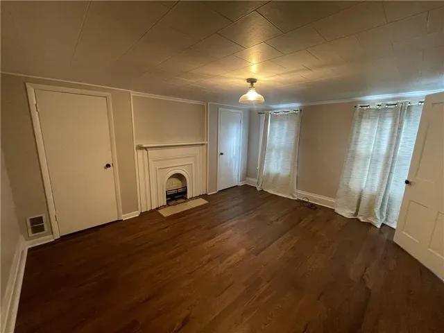 an empty room with wooden floor and a fireplace