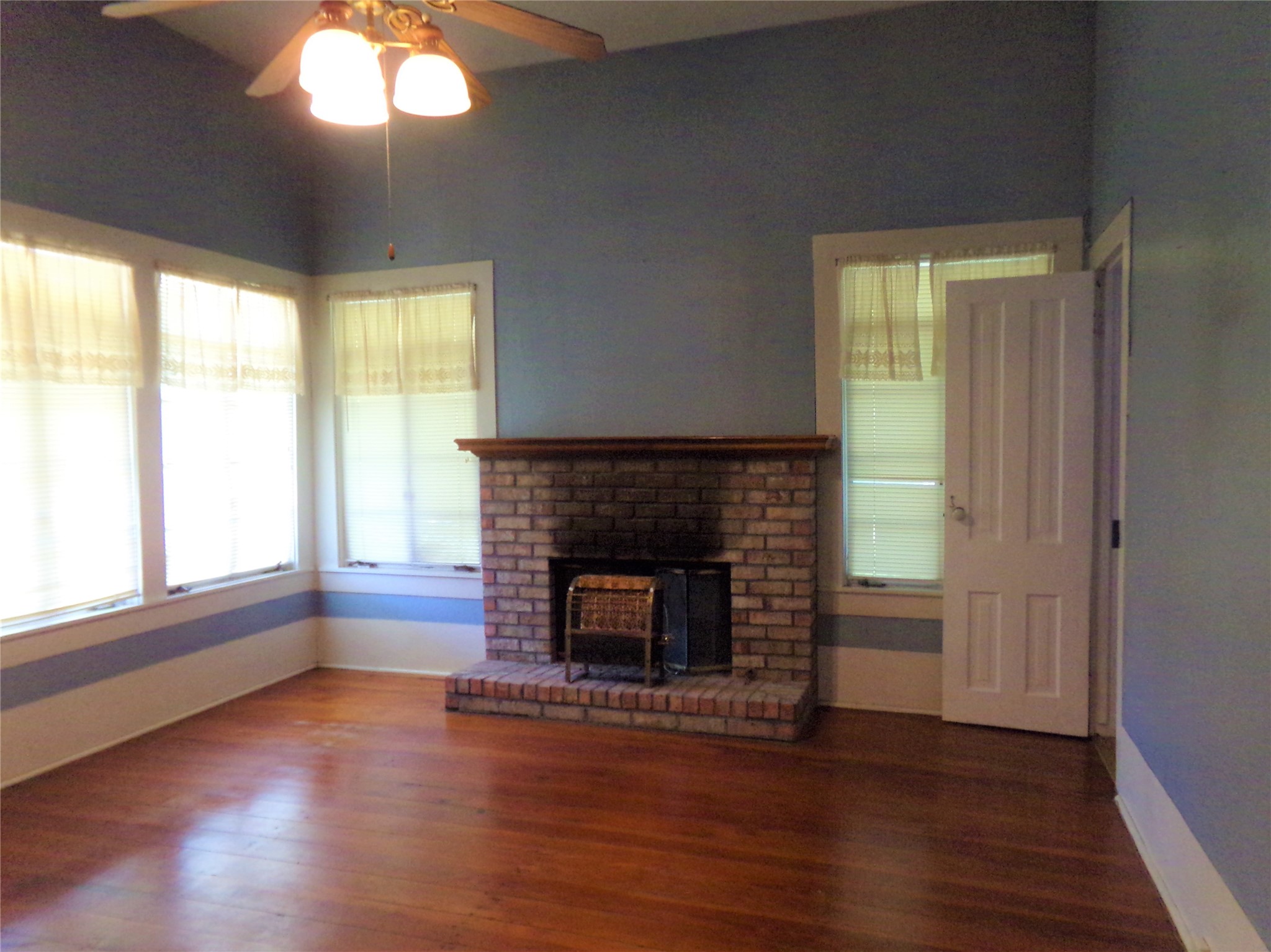 300 South Summit Street Weimar, TX 78962 - Photo 16 of 27 an empty room with wooden floor fireplace and windows