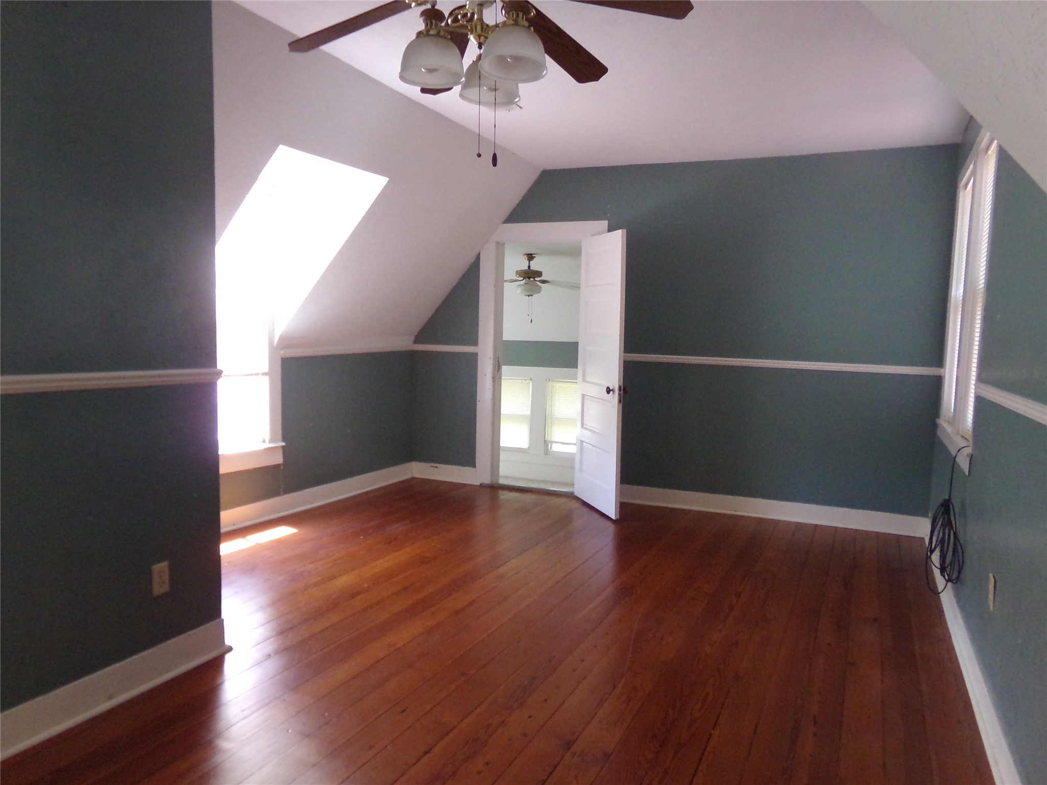 300 South Summit Street Weimar, TX 78962 - Photo 22 of 27 an empty room with wooden floor chandelier fan and windows