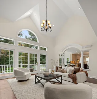 a living room with furniture a chandelier and a large window