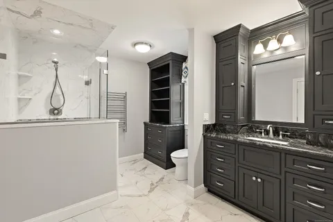 a bathroom with a granite countertop sink a toilet and a mirror