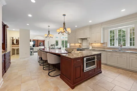 a kitchen with kitchen island granite countertop a stove a sink a dining table and chairs