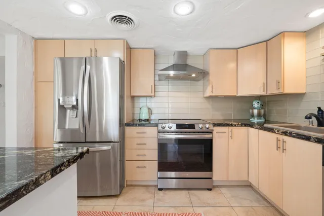 a kitchen with granite countertop a refrigerator stove and cabinets