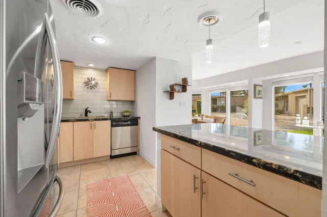 a kitchen with granite countertop a stove a sink and a refrigerator