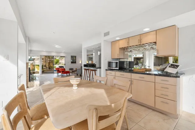 a kitchen with stainless steel appliances kitchen island granite countertop a table chairs sink and cabinets