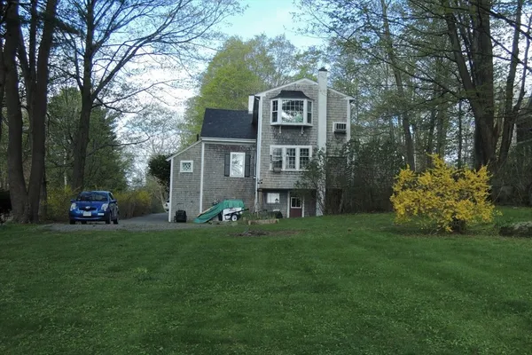 a front view of a house with a garden and trees
