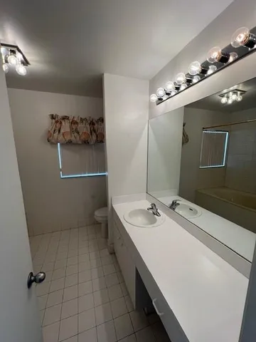 a bathroom with a double vanity sink a toilet and mirror