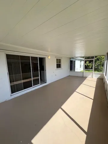a view of an empty room with wooden floor and windows
