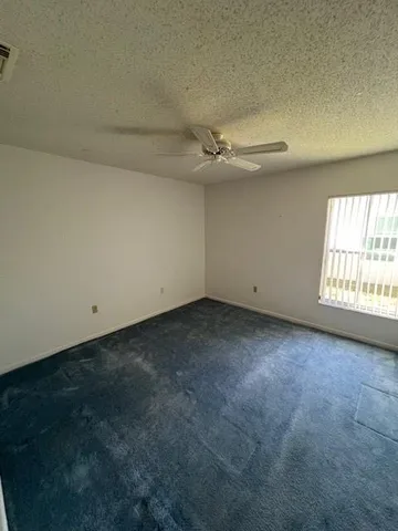 an empty room with a ceiling fan and window
