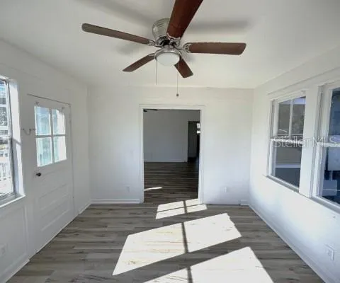 a view of an empty room with a window and wooden floor