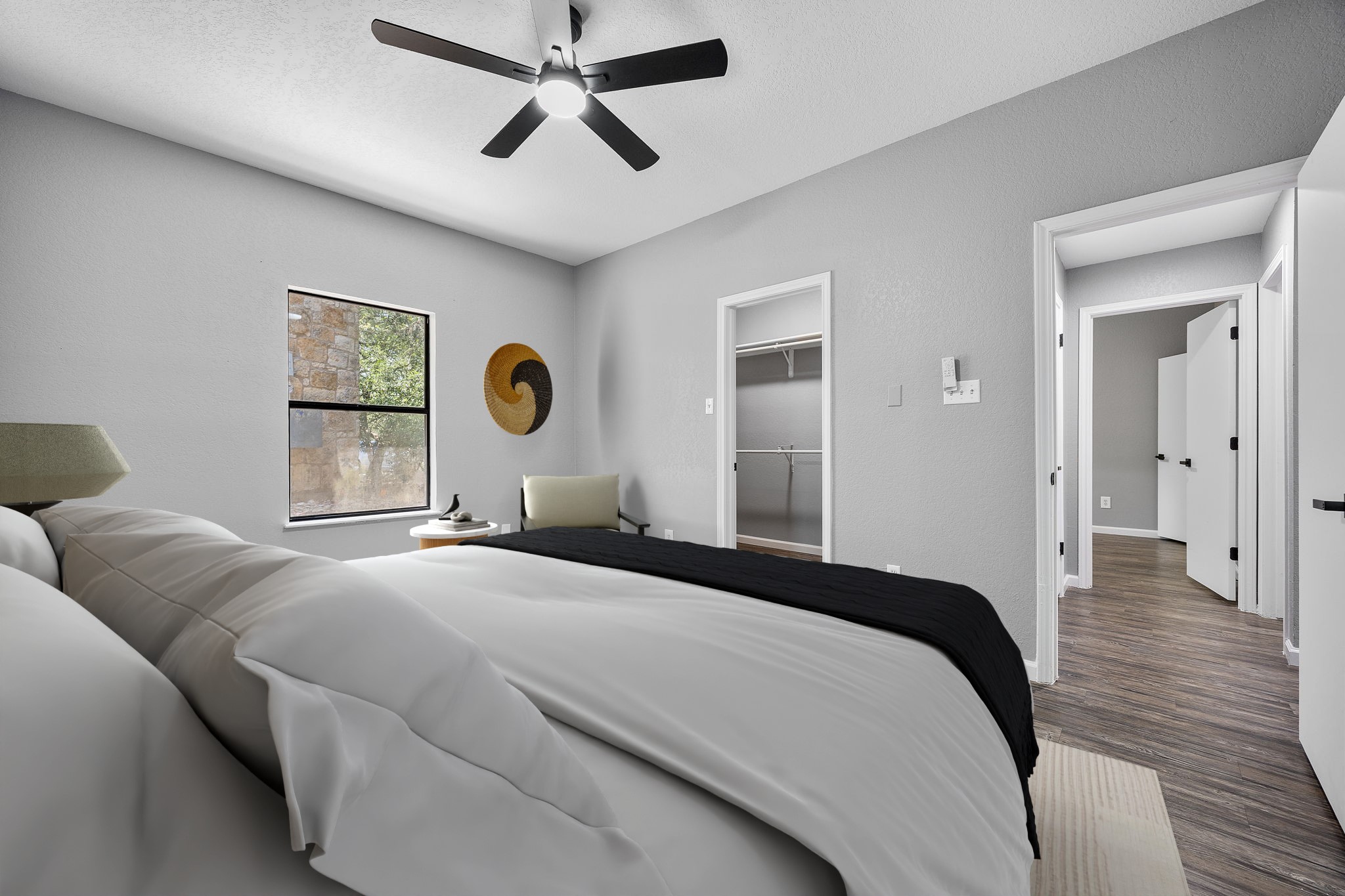 4711 Spicewood Springs Road, Unit 1106 Austin, TX 78759 - Photo 9 of 19 Room featuring a dark-toned ceiling fan, a window with exterior stone and foliage visible, light gray wall paint, and wood-finish flooring