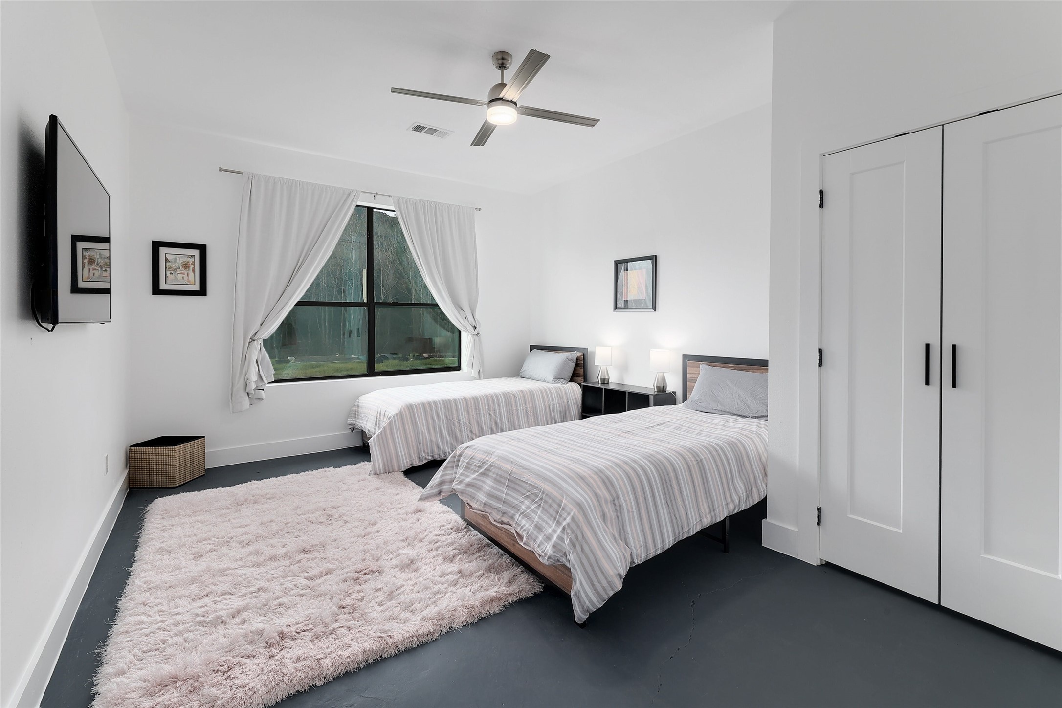 7001 Ranch Road 2222 Austin, TX 78730 - Photo 14 of 18 Two comfortable beds await in this bright, naturally illuminated bedroom, complete with a ceiling fan for year-round comfort.