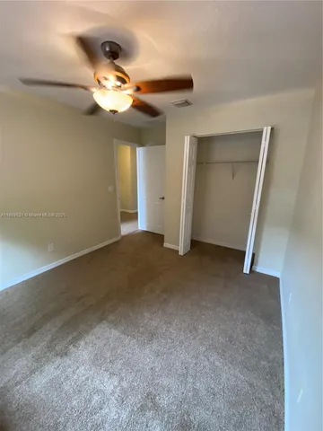 en empty room with windows and chandelier fan