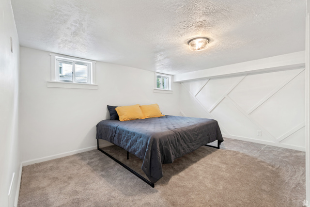 4883 South Center Street Murray, UT 84107 - Photo 22 of 32 Bedroom 2. Carpeted room featuring a decorative accent wall with geometric paneling, two windows, and a flush-mount ceiling light fixture