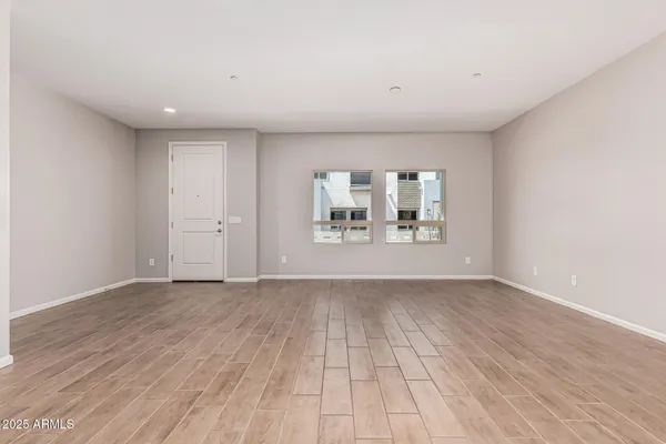 a view of an empty room with a window and wooden floor