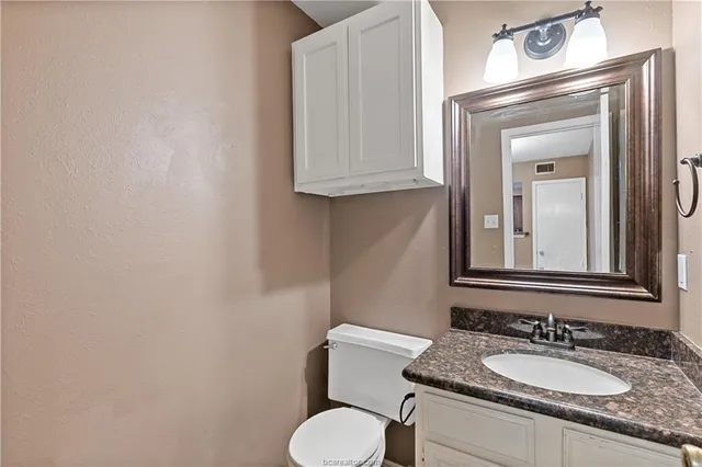 a bathroom with a granite countertop toilet sink and mirror