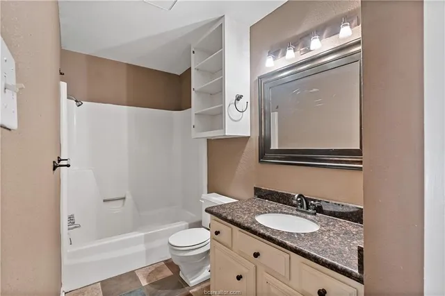 a bathroom with a granite countertop sink toilet and shower