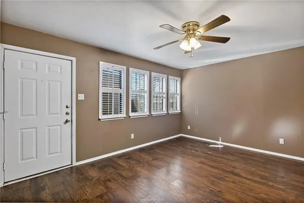 a view of an empty room with window and wooden floor