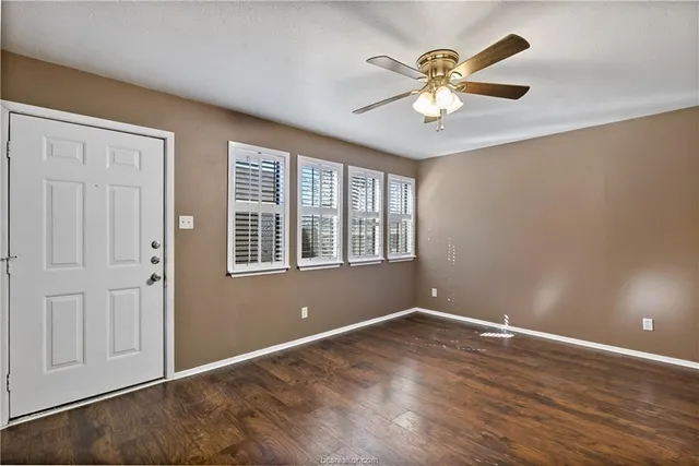 a view of an empty room with window and wooden floor
