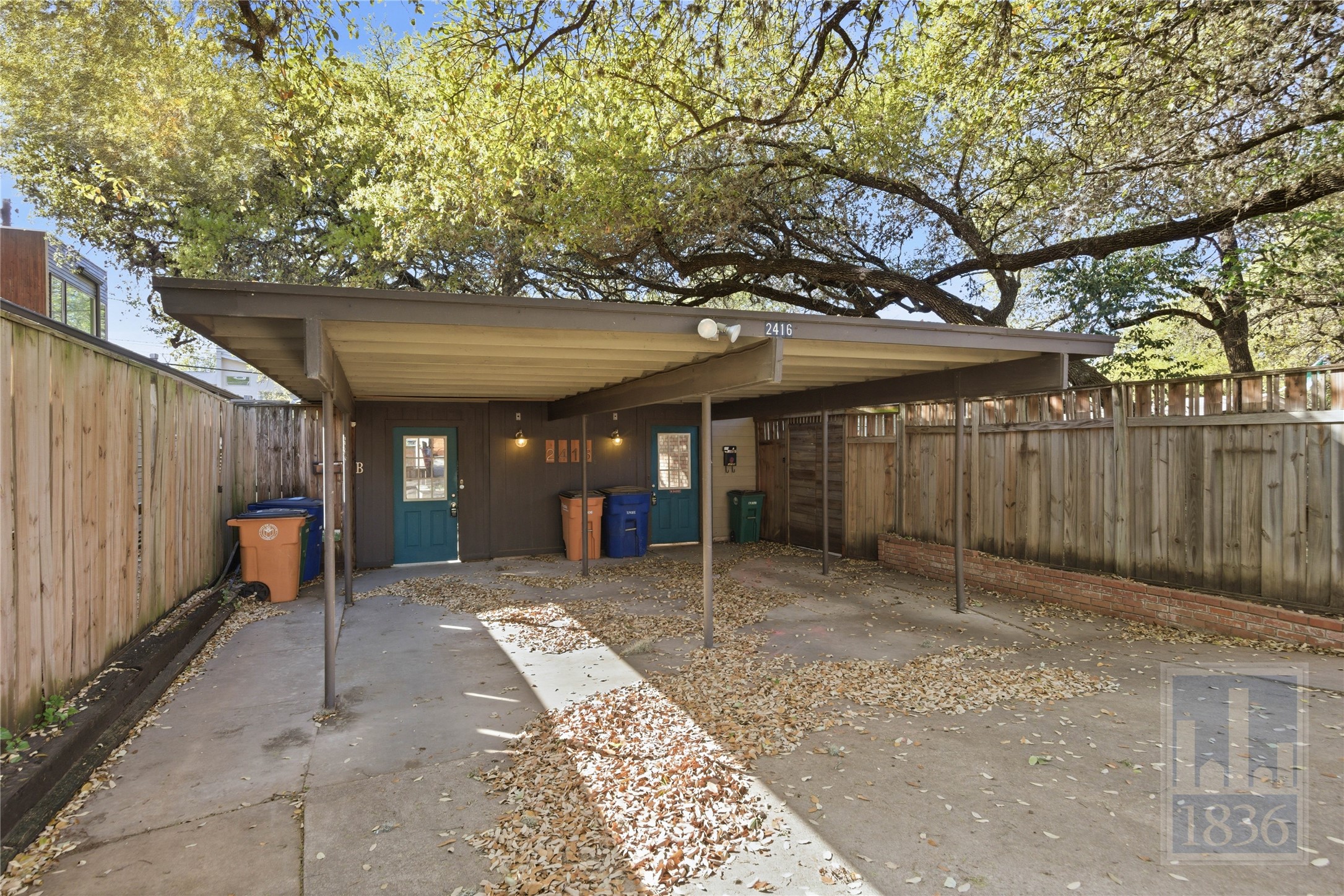 2416 South 5th Street, Unit B Austin, TX 78704 - Photo 24 of 28 a view of a patio with a table and chairs under an umbrella with wooden fence
