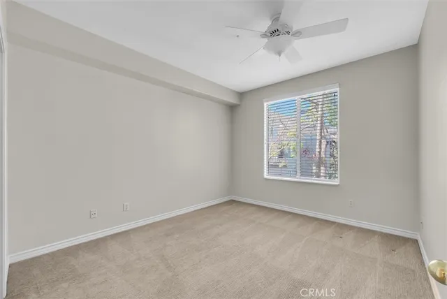 an empty room with a window and a ceiling fan
