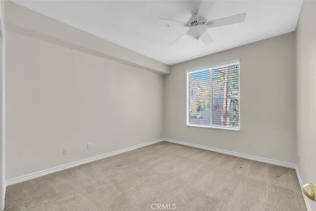 an empty room with a window and a ceiling fan