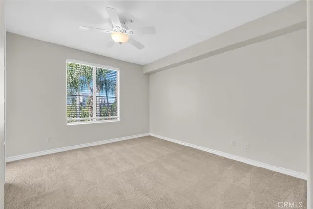 an empty room with a window and a ceiling fan