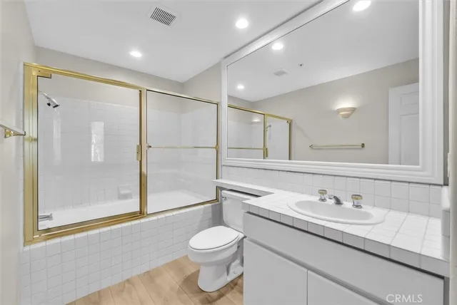 a bathroom with a granite countertop sink a toilet and shower