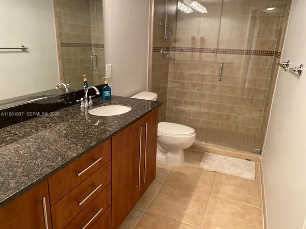 a bathroom with a granite countertop sink a toilet a mirror and shower