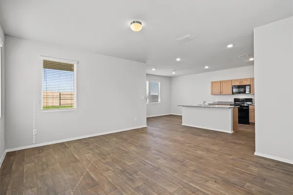 a view of kitchen with kitchen island wooden floor and stainless steel appliances