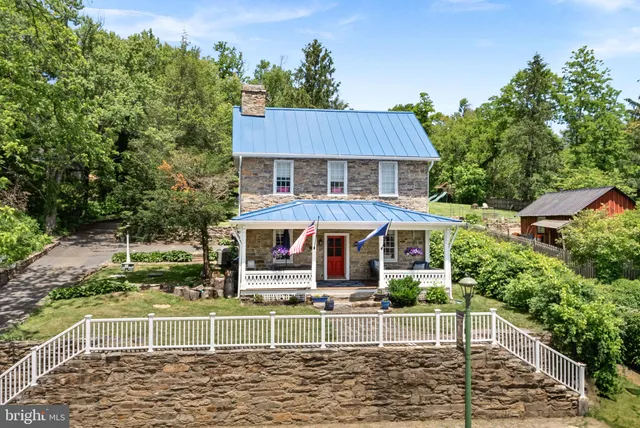 a view of a white house with large windows and a yard with plants and a yard