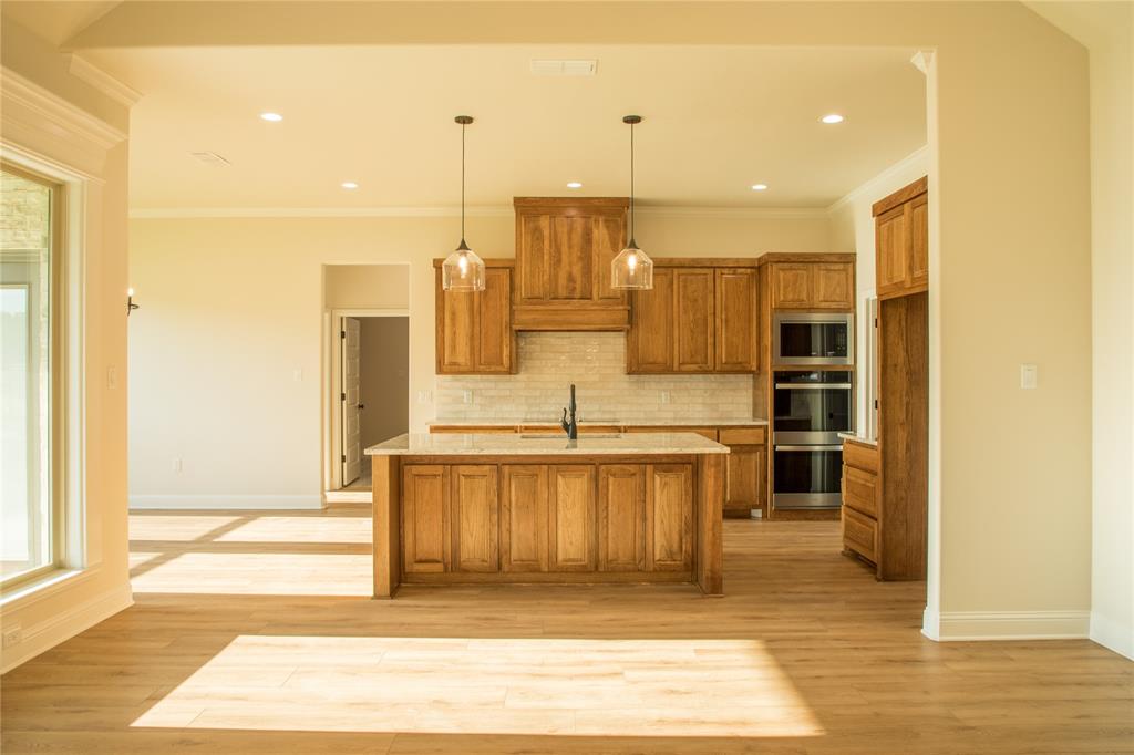 141 Prairie Winds Drive Poolville, TX 76487 - Photo 9 of 15 a view of a kitchen with kitchen island a sink stainless steel appliances and cabinets