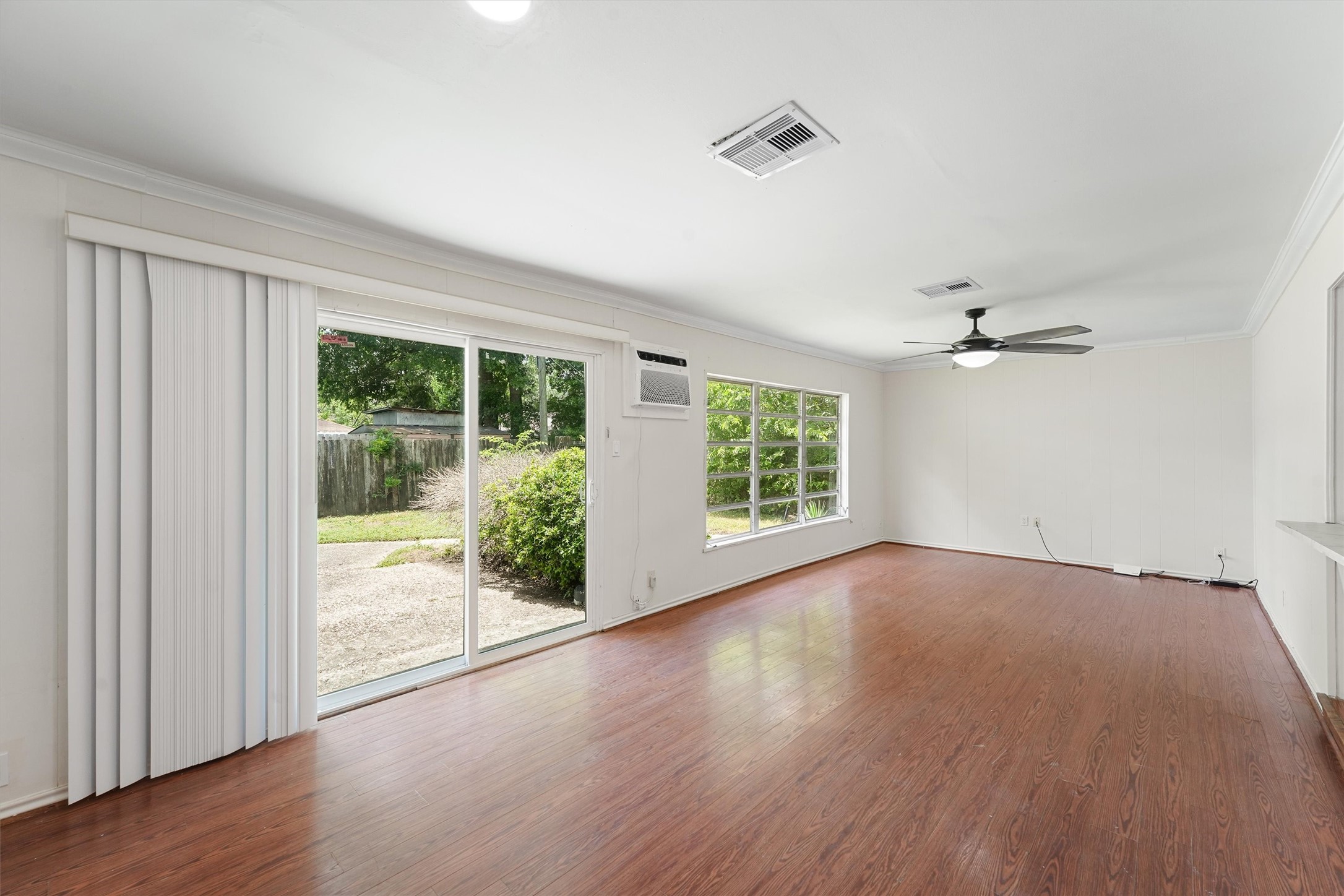 5826 Belmark Street Houston, TX 77033 - Photo 2 of 15 an empty room with wooden floor fan and windows