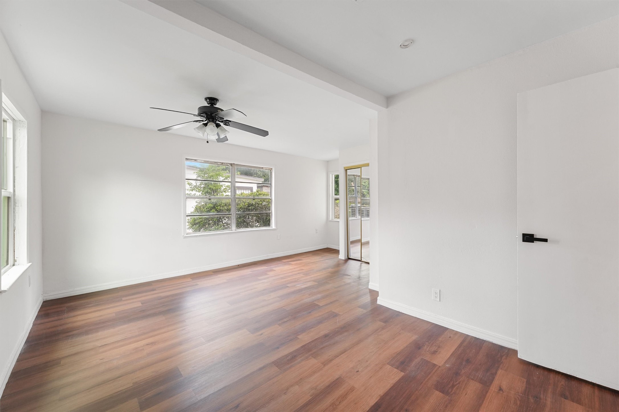 5826 Belmark Street Houston, TX 77033 - Photo 10 of 15 an empty room with wooden floor chandelier fan and windows
