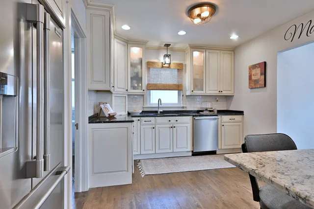 a kitchen with kitchen island granite countertop wooden cabinets a sink a stove a refrigerator and island