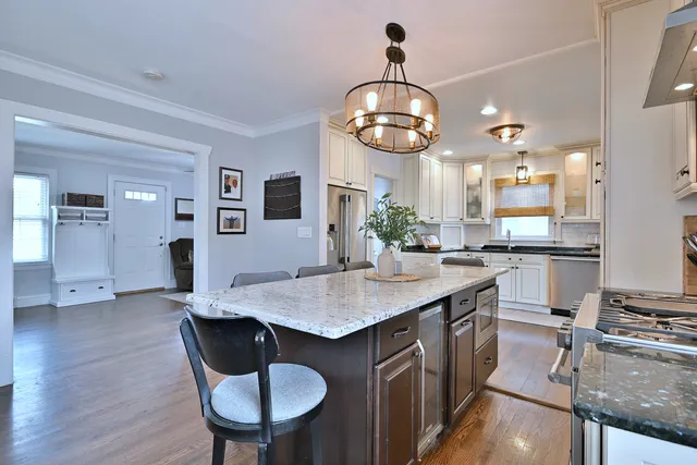 a kitchen with stainless steel appliances granite countertop a sink a stove and chairs