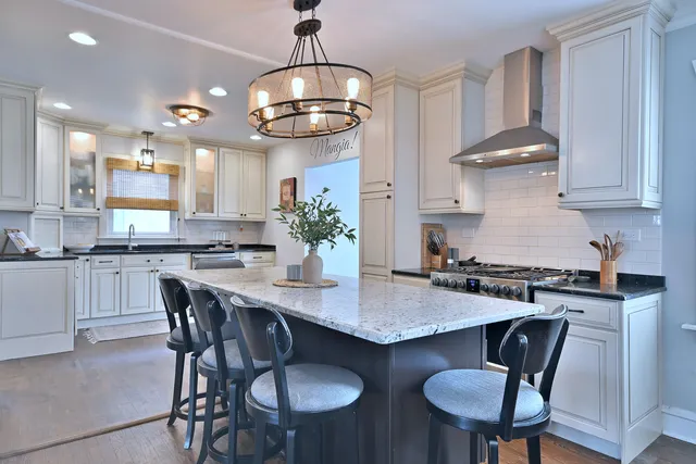 a kitchen with stainless steel appliances granite countertop a stove a kitchen island a dining table and chairs