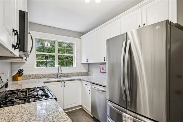 a kitchen with stainless steel appliances a refrigerator sink and window