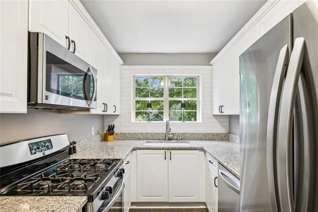 a kitchen with stainless steel appliances granite countertop a stove a sink and a refrigerator