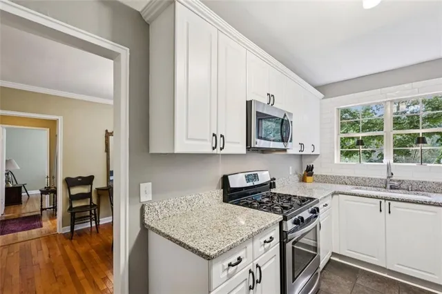 a kitchen with granite countertop a sink stove and cabinets
