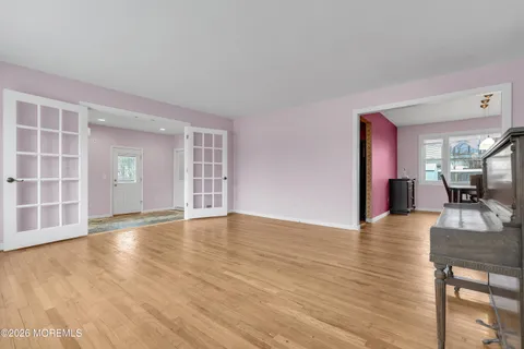 a view of an empty room with window and wooden floor