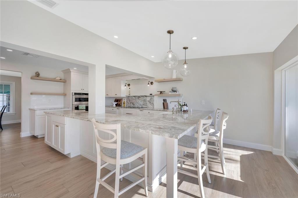 1925 Tarpon Road Naples, FL 34102 - Photo 16 of 41 a large kitchen with dining table chairs and wooden floor