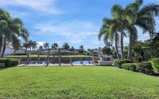 a view of a swimming pool with lawn chairs and a big yard