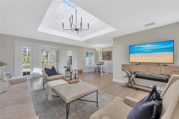 a living room with furniture a flat screen tv and a chandelier