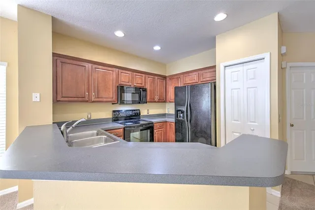 a kitchen with stainless steel appliances granite countertop a refrigerator a stove and a sink with wooden cabinets