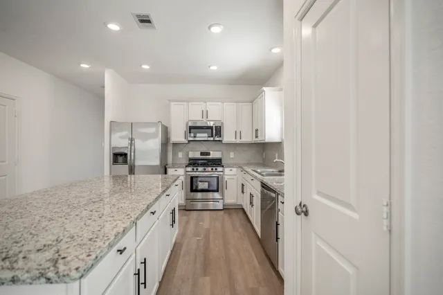a large kitchen with stainless steel appliances granite countertop a lot of counter space and a sink