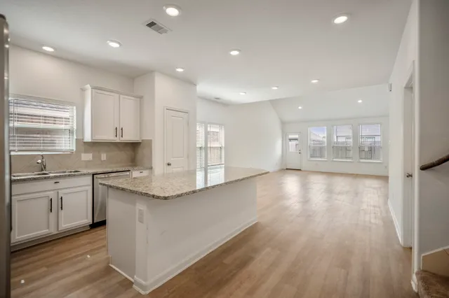 a large kitchen with stainless steel appliances granite countertop a large counter top and a wooden floors